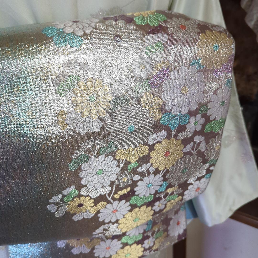 虹色に煌めくシルバーの地に、菊の花が艶やかに咲く、美しい正絹袋帯です