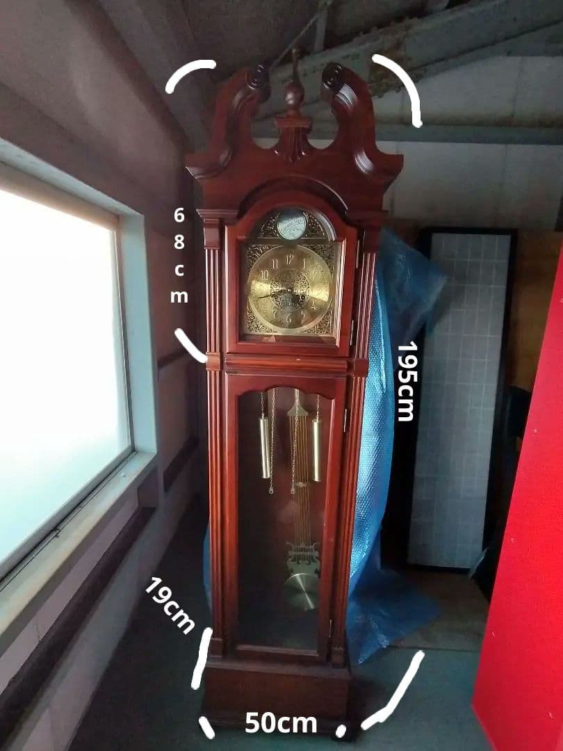 装飾的な文字盤と振り子を持つダークウッドの柱時計