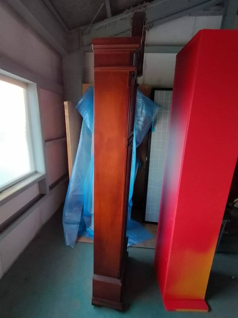 装飾的な文字盤と振り子を持つダークウッドの柱時計