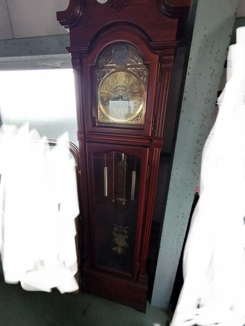 装飾的な文字盤と振り子を持つダークウッドの柱時計