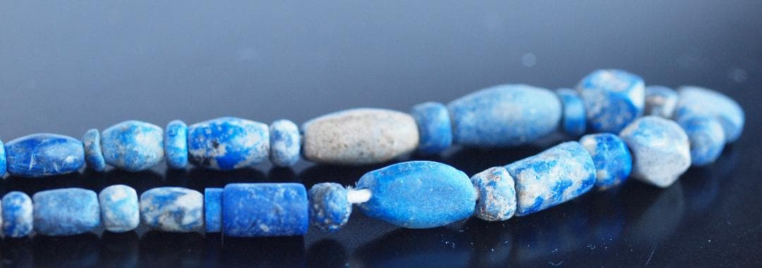 古代濃紺ラピスの管玉や丸玉をほぼ左右対称に編み、トップに斧型や多面体、80個の連