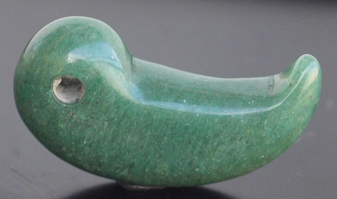 光にかざすと薄緑の細い帯状紋が出現、頭・胴の間には沈線、ずんぐり形の勾玉　沖縄の